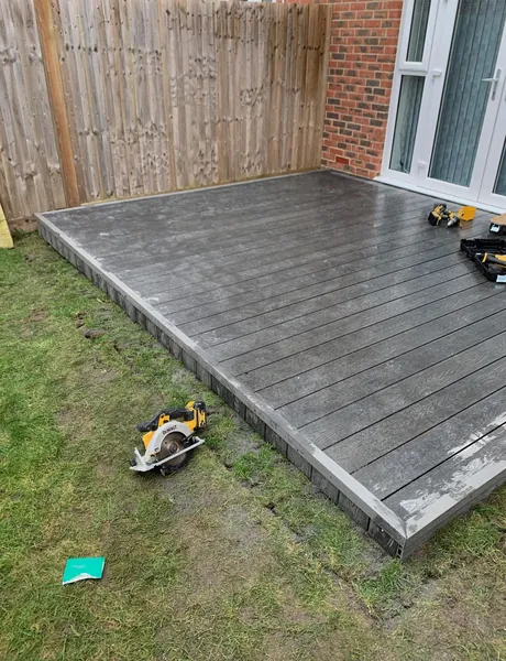 Grey composite decking being installed beside French doors – decking for homes in Havant